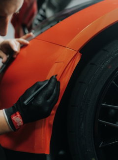 a-man-is-working-on-an-orange-car.jpg a man is working on an orange car
